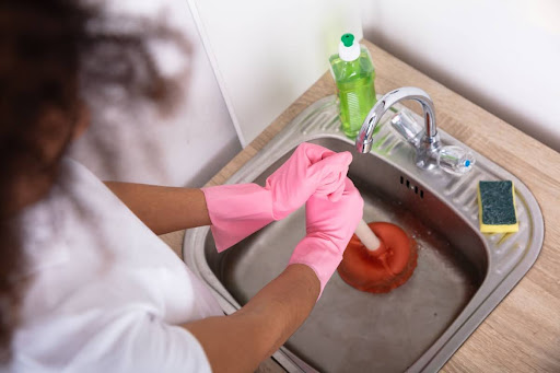 A woman plunging a clogged kitchen sink.
