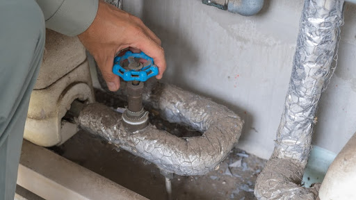 Homeowner turning water supply shutoff valve.