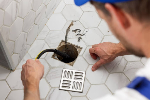 Plumber cleaning clogged shower drain.