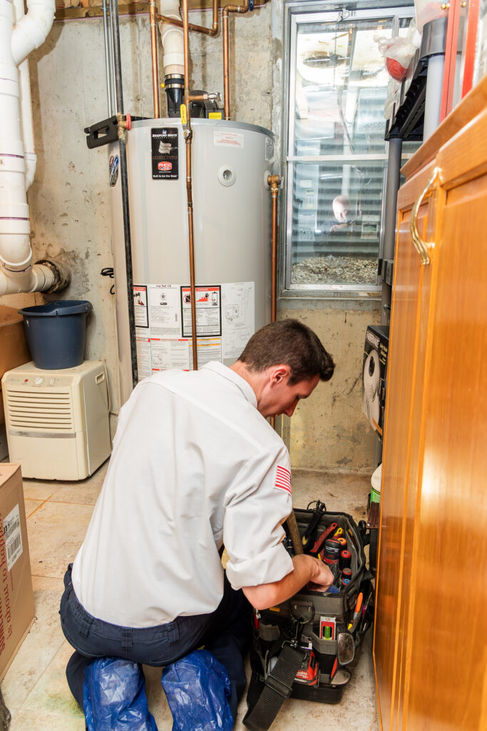 An S and J Plumbing & Sewer technician works on a water heater.