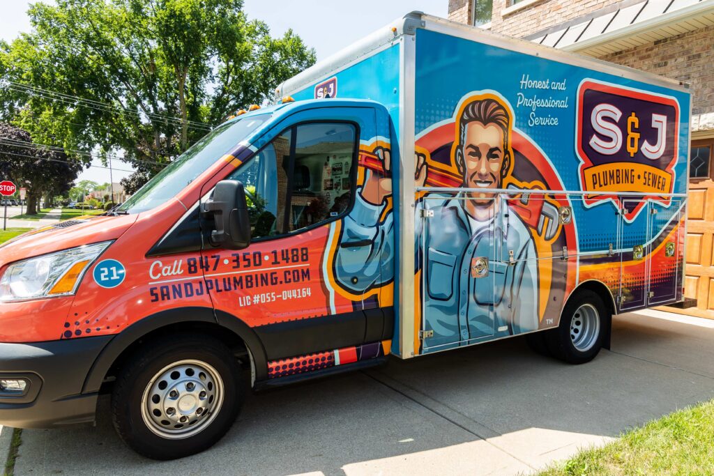An S and J Plumbing & Sewer truck parked outside of a home.
